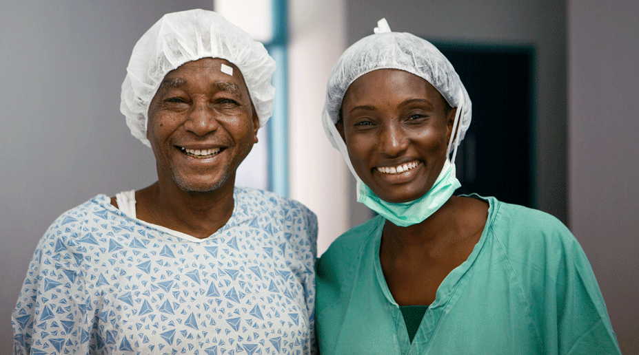 A smiling cataract patient stands beside a healthcare worker after successful eye surgery.