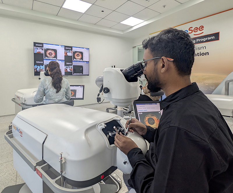 A surgeon practices delicate cataract surgery techniques on a HelpMeSee virtual reality simulator while another trainee works in the background.