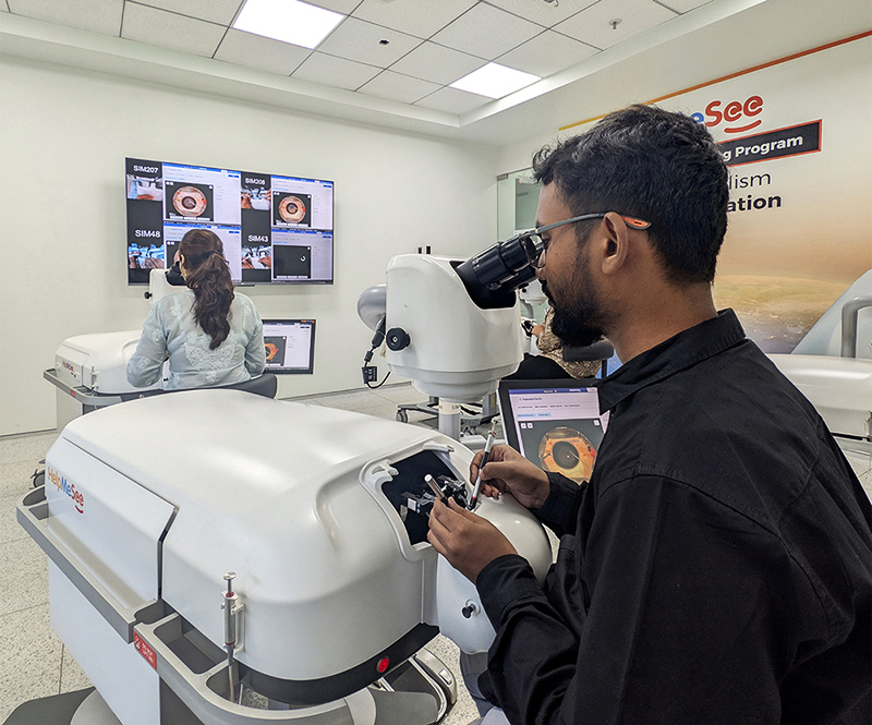 A surgeon practices delicate cataract surgery techniques on a HelpMeSee virtual reality simulator while another trainee works in the background.